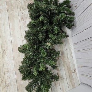 May include: A long, green garland of artificial pine branches, perfect for decorating for the holidays.