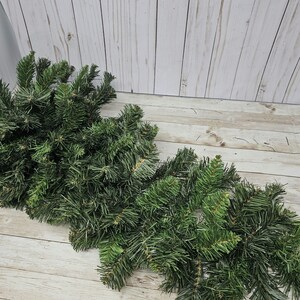 May include: Two bundles of artificial pine sprigs, perfect for crafting wreaths, garlands, or other holiday decor.