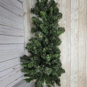 May include: A long, green artificial pine garland with lush, full branches. The garland is perfect for adding a touch of greenery to your home decor.