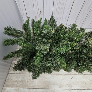 May include: A bunch of green artificial pine branches, perfect for crafting wreaths or garlands.