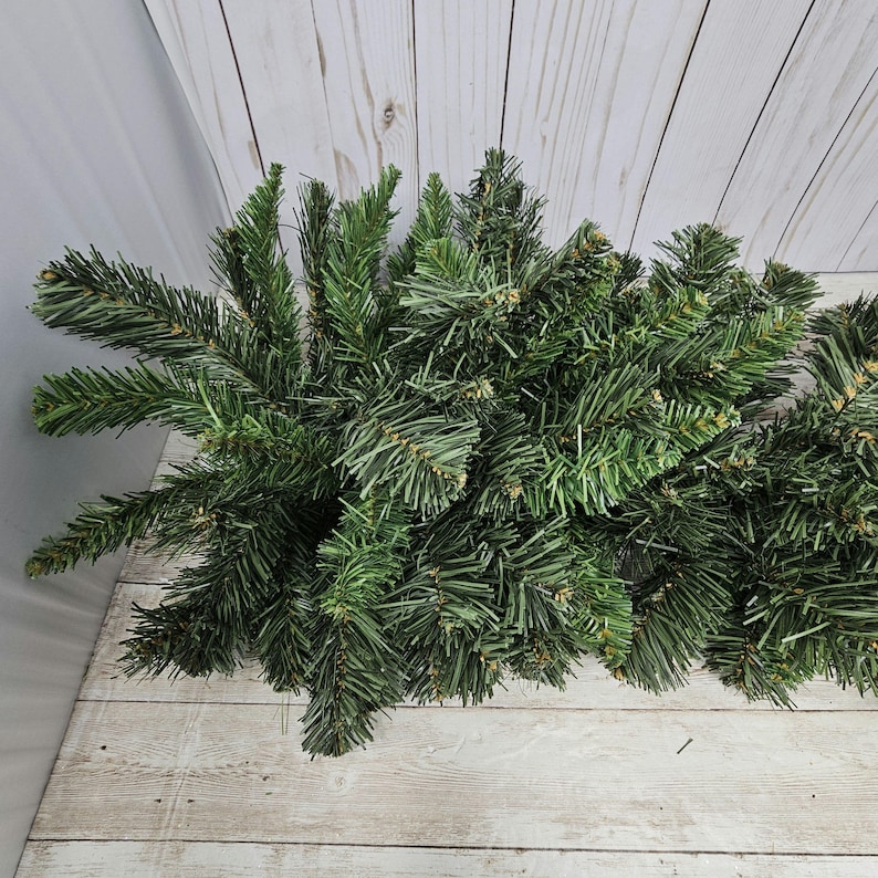 May include: A bunch of green artificial pine branches, perfect for crafting wreaths or garlands.