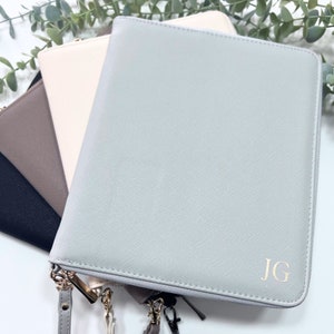 May include: A grey leather zippered notebook with gold hardware and the initials "JG" embossed on the front.