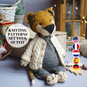 May include: A knitted tiger toy, dressed in a cream cable-knit cardigan and grey overalls. The tiger has a yellow and black striped head, black nose, and button details. The text "KNITTING PATTERNS SET TOYS & OUTFIT" is visible.
