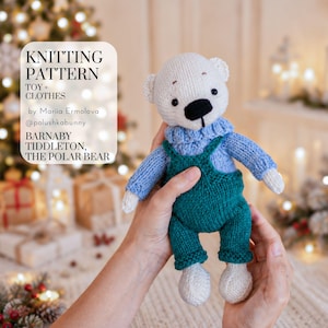 Op de afbeelding: Een gebreide ijsbeer met een lichtblauwe trui en een donkergroene tuinbroek. De tekst op de afbeelding luidt: KNITTING PATTERN TOY + CLOTHES by Mariia Ermolova @polushkabunny BARNABY TIDDLETON, THE POLAR BEAR. De beer heeft witte vacht.