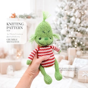 Pode incluir: Um brinquedo de malha com cabeça verde, um tufo de cabelo, um sorriso bordado e olhos pretos. O corpo tem listras horizontais vermelhas e brancas, enquanto os braços e pernas são verdes. Texto: KNITTING PATTERN TOY by Mariia Ermolova @polushkabunny GRUMBLE MISTLETOE.