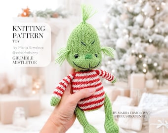 Peut inclure: Un jouet tricoté avec une tête verte, une touffe de cheveux, un sourire brodé et des yeux noirs. Le corps présente des rayures horizontales rouges et blanches, tandis que les bras et les jambes sont verts. Texte : KNITTING PATTERN TOY by Mariia Ermolova @polushkabunny GRUMBLE MISTLETOE.