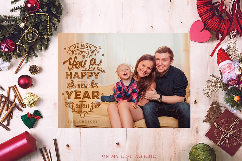 K&ouml;nnte beinhalten: Eine Weihnachtskarte mit einem Familienportr&auml;t und dem Text &bdquo;Wir w&uuml;nschen Ihnen ein frohes neues Jahr 2020&ldquo;. Die Familie l&auml;chelt. Festliche Dekorationen umgeben die Karte, darunter ein Kranz und Ornamente.