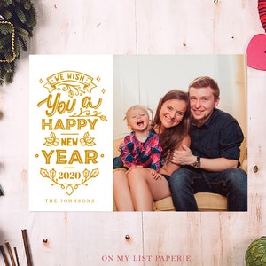 K&ouml;nnte beinhalten: Eine Neujahrskarte mit einem Familienfoto und goldenen Buchstaben mit der Aufschrift "We wish you a Happy New Year 2020". Die Karte ist mit festlichen Feiertagselementen wie Ornamenten und Gr&uuml;n geschm&uuml;ckt. Die Familie l&auml;chelt.