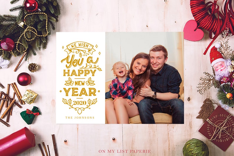 K&ouml;nnte beinhalten: Eine Neujahrskarte mit einem Familienfoto und goldenen Buchstaben mit der Aufschrift "We wish you a Happy New Year 2020". Die Karte ist mit festlichen Feiertagselementen wie Ornamenten und Gr&uuml;n geschm&uuml;ckt. Die Familie l&auml;chelt.