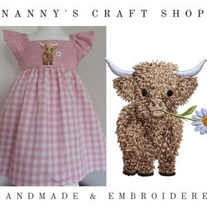 Op de afbeelding: Een roze en wit geruite jurk met vlindermouwen en een vierkante halslijn. Het lijfje is voorzien van een geborduurde bruine Schotse Hooglander die een wit madeliefje vasthoudt. De tekst Nanny's Craft Shop en Handmade & Embroidered is zichtbaar.
