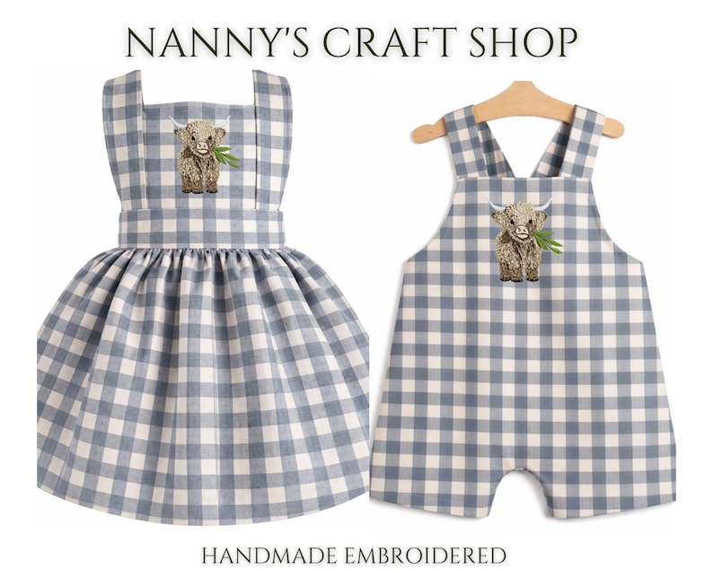 Pode incluir: Dois conjuntos infantis com padr&atilde;o xadrez azul e branco. Um &eacute; um vestido, o outro um macac&atilde;o. Ambos apresentam um bordado de vaca Highland e o texto "Nanny's Craft Shop". "Handmade Embroidered" tamb&eacute;m &eacute; vis&iacute;vel.