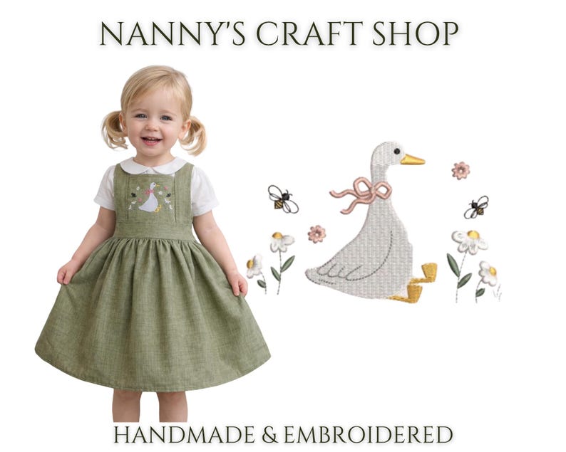 Op de afbeelding: Een saliegroene overgooier over een wit overhemd met kraag. De jurk is voorzien van een borduursel van een witte gans met een roze lint, omringd door kleine bloemen en bijen. De tekst NANNY'S CRAFT SHOP HANDMADE & EMBROIDERED is aanwezig.