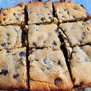 Puede incluir: Nueve cuadrados de barras de galletas con chispas de chocolate reci&eacute;n horneadas. Las barras son de color marr&oacute;n dorado con chispas de chocolate visibles. Los cuadrados est&aacute;n cortados y listos para servir.