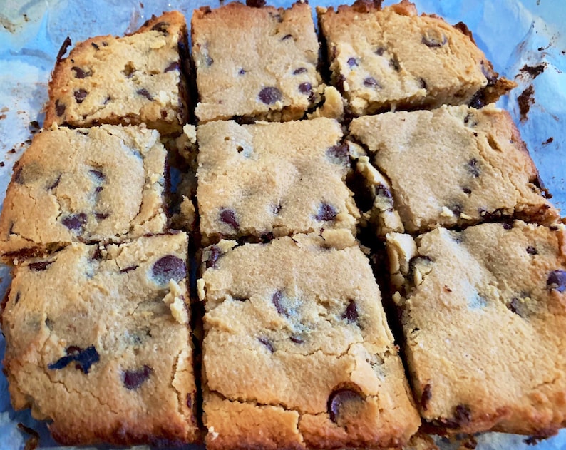 Puede incluir: Nueve cuadrados de barras de galletas con chispas de chocolate reci&eacute;n horneadas. Las barras son de color marr&oacute;n dorado con chispas de chocolate visibles. Los cuadrados est&aacute;n cortados y listos para servir.