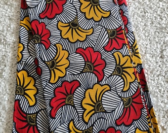 May include: Red, yellow, and black floral print fabric with a white background. The fabric has the text "Guaranteed Wax Block" and "Veritable Wax Block Prints Sanne V" printed on it.