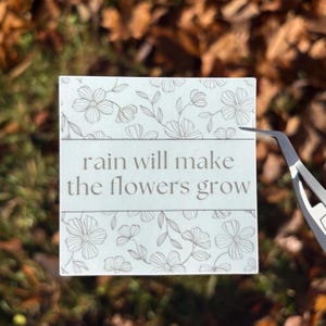 Regn får blommorna att växa: inspirerande klistermärke eller magnet