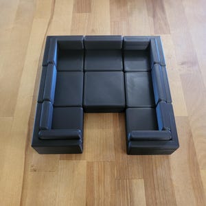 May include: A black modular sectional sofa with a U-shaped configuration. The sofa is made up of individual pieces that can be arranged in different ways.