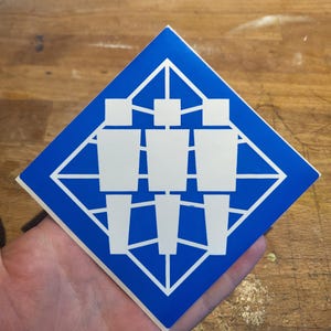 May include: A blue diamond-shaped sticker with a white design of three stylised figures standing in a grid pattern.