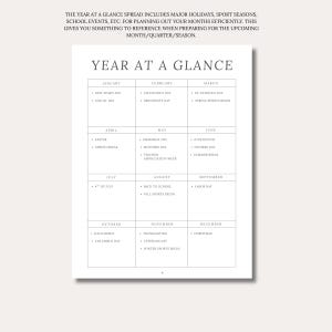 May include: A white paper planner page titled YEAR AT A GLANCE with a grid layout organized by month from January to December. Each month box lists specific holidays and events like New Year's Day, Valentine's Day, and Christmas in black text.