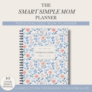 May include: A spiral-bound weekly planner with a white cover featuring a floral pattern of blue and peach flowers. The center label reads "SMART SIMPLE MOM WEEKLY PLANNER allyson marie". The top text reads "THE SMART SIMPLE MOM PLANNER".
