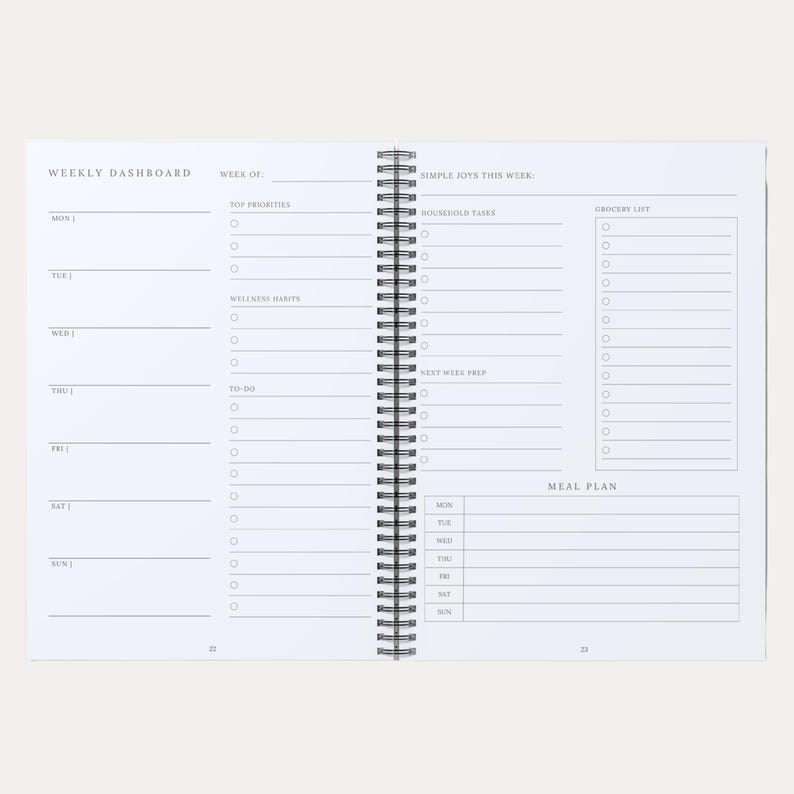 May include: A white spiral-bound weekly planner open to two pages. The left page features a Weekly Dashboard with daily sections. The right page includes sections for Simple Joys, Household Tasks, Grocery List, Next Week Prep, and a Meal Plan.