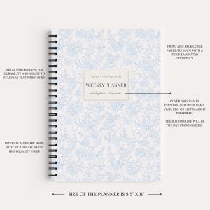 May include: A weekly planner measuring 8.5 inches by 11 inches with a light blue and white floral pattern. It features a black metal wire binding, a central label with the text SMART SIMPLE MOM WEEKLY PLANNER, and a space for personalization.