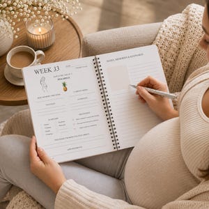 May include: A spiral-bound pregnancy journal open to a page titled Week 33, featuring sections for notes, memories, keepsakes, symptoms, and milestones. The page includes a small pineapple illustration and text prompts for tracking weekly progress.