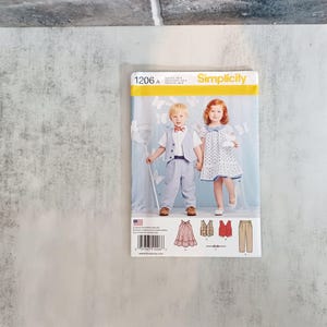 May include: Simplicity sewing pattern 1206 A featuring children's clothing. The pattern shows a boy in a vest, bow tie, and pants, and a girl in a polka dot dress. The pattern includes illustrations of the clothing items and a barcode.