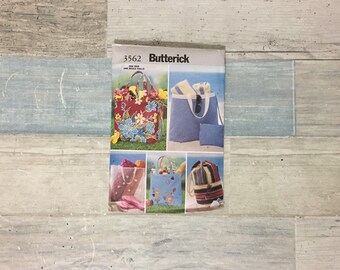 May include: A Butterick pattern envelope, number 3562, featuring images of various tote bags. The bags showcase floral, striped, and patterned designs. The envelope is on a light blue and gray wooden surface.