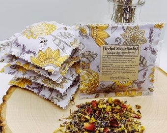Puede incluir: Una pila de pequeños saquitos de tela floral llenos de hierbas y flores secas. Los saquitos están etiquetados con "Herbal Sleep Sachet Infused with Essential Oils". La etiqueta enumera los ingredientes: capullos de lavanda, flores de manzanilla, melisa, caléndula seca, pétalos de rosa, hibisco, aciano, aceite esencial de lavanda y salvia esclarea de grado terapéutico. La etiqueta también incluye instrucciones: "Colóquelo dentro de su funda de almohada o al lado de usted. Puede triturar suavemente las hierbas para liberar el aroma si desea un aroma más fuerte. Refresque periódicamente. El saquito individual es para un aroma más fuerte."