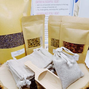 May include: An assortment of aromatherapy supplies, including small linen bags, dried herbs in kraft paper pouches, a wooden scoop, and a small amber glass bottle. The image features instructions for making lavender sachets.