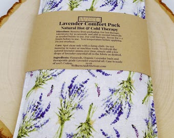 Puede incluir: Un cojín térmico rectangular de algodón con tela blanca y un estampado de ramas de lavanda moradas y verdes. Una etiqueta de papel marrón envuelve el centro con el texto Lavender Comfort Pack, Natural Hot & Cold Therapy.