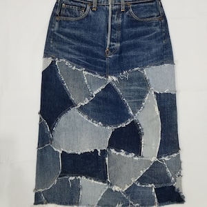 May include: A long denim skirt made from patchwork denim in various shades of blue. The skirt has a high waist and a raw hem.