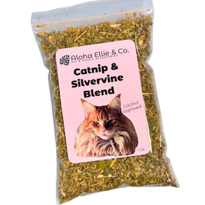May include: A clear plastic bag filled with dried green herbs. A pink label reads "Catnip & Silvervine Blend" with a cat illustration and "Aloha Ellie & Co." branding. The bag contains 1 oz of product.
