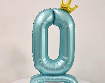 Pode incluir: Balão azul claro em forma do número zero, encimado por uma coroa dourada. O balão está sobre uma superfície branca. Ideal para um aniversário ou celebração. Aproximadamente 76 cm de altura.