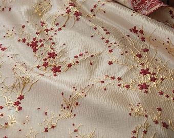 May include: Beige fabric with a raised embossed pattern of gold branches and red flowers. The fabric has a subtle texture.