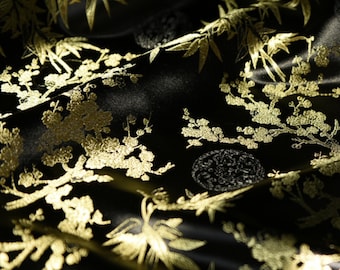 May include: Black fabric with a gold floral pattern. The pattern features stylized flowers and leaves.