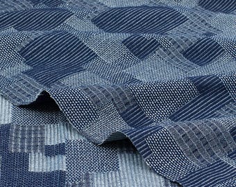 May include: Blue and white woven fabric with a geometric pattern. The fabric has a textured surface and a subtle sheen.