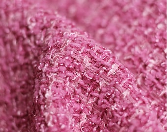 May include: Close-up of a pink textured fabric with a fuzzy, boucle-like texture.