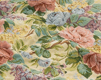 May include: A tapestry fabric with a floral pattern featuring pink, blue, and yellow roses, green leaves, and purple flowers. The fabric has a textured, woven look.