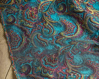 Peut inclure: Tissu turquoise avec un motif paisley en or et bordeaux. Le tissu a une apparence texturée, presque scintillante.