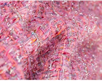 May include: Close-up of a pink and silver tweed fabric with a textured, woven pattern. The fabric has a shimmery, iridescent finish.