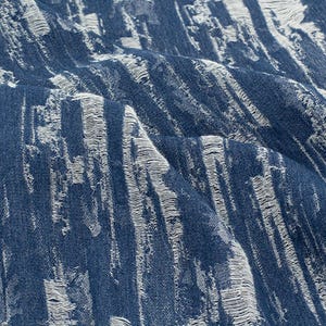 Puede incluir: Tela vaquera azul con un patrón texturizado blanco de líneas verticales. La tela tiene un aspecto ligeramente desgastado.