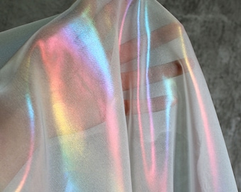 May include: A sheer iridescent fabric with a rainbow sheen. The fabric is draped and folded, showing the iridescent effect.