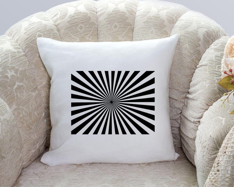 K&ouml;nnte beinhalten: Ein wei&szlig;es Kissen mit einem schwarz-wei&szlig;en Sonnenstrahlen-Design. Das Design ist mittig auf dem Kissen platziert und hat einen schwarzen Kreis in der Mitte.