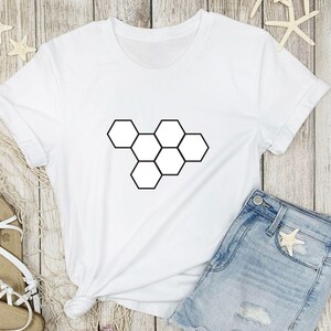 May include: White t-shirt with a black geometric honeycomb design.