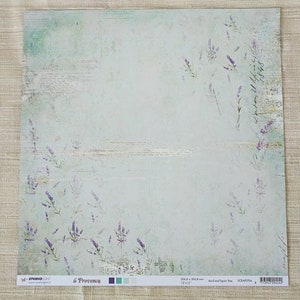 Puede incluir: Papel de scrapbooking cuadrado con un fondo de acuarela azul claro y verde. Ramas de lavanda y acentos de escritura están dispersos por el papel. El texto "la Provence" y "304,8 x 304,8 mm" son visibles. El papel es libre de ácido y lignina.