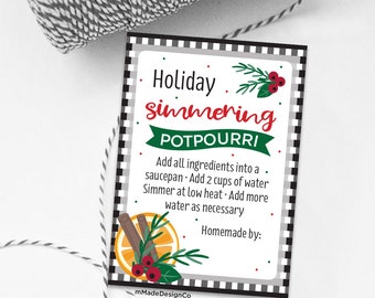 以下が含まれることがあります： 赤と緑で「Holiday simmering POTPOURRI」と書かれた装飾的なタグ。ポプリの作り方の説明、シナモンスティック、オレンジスライス、ベリーのイラストが描かれています。白と黒のチェック柄のボーダーが付いています。