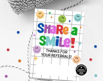 May include: A white card with the text "Share a Smile! Thanks for your referrals!" in colourful letters and smiley face graphics. The card has a grid pattern and a black and white string is in the background.