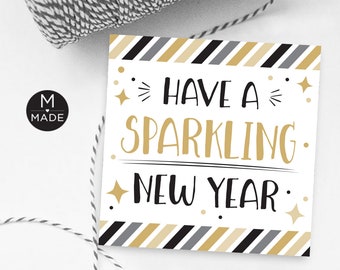 Può includere: Biglietto quadrato bianco con la scritta "Have a Sparkling New Year" in lettere nere e dorate. Il biglietto ha un bordo a righe in nero, oro e grigio. Sullo sfondo un cordino bianco e nero.